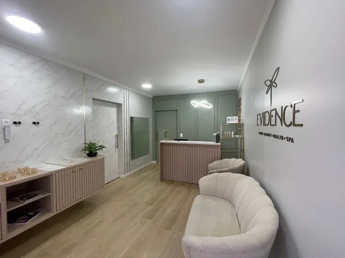 Recepção da Evidence Clinic, com o nome em relevo na parede, bancada de mármore e poltronas claras.